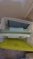 Two clear plastic storage bins with four various plastic lids stacked inside and in front.
