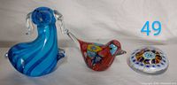 Three vintage glass paperweights displayed on white background showing dog, bird, and round patterned shapes