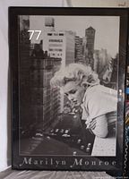 Framed black and white poster featuring Marilyn Monroe looking down over a balcony with a city street background.