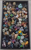 Top view of a tray containing a large assortment of small plastic toy figures from the Pets movie in various poses and colors.