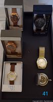 Five watches arranged on display tray including Time and Tru watches, black watch, George watch with gold-tone bracelet, and James Michael pocket watch