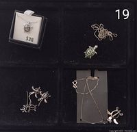 Photo showing the entire lot laid out on a black velvet background with 3 turtle earrings, 3 necklaces with turtle pendants, and one separate turtle pendant.