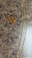 Chain and cufflinks laid flat on countertop to show overall contents