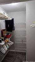 Closet interior showing wire shelving with plastic hangers and folded clothing.