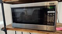 Front view of the Panasonic Inverter NN-SA651S microwave oven on wooden surface, showing stainless steel body and control panel on right side.
