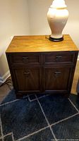 Front view of the Asian style Century end table with visible drawer and cabinet doors, wood grain top surface with some wear, and lamp placed on top.