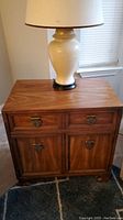 Side table with lamp on top showing front view, two drawers and cabinet below