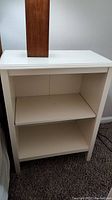 Front view of white painted side table showing two shelves with one removable shelf.