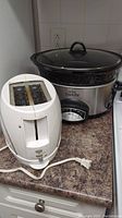 Toaster and crock pot on countertop showing Sunbeam toaster and Rival crock pot with glass lid
