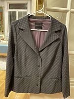Photo of Bitte Kai Rand Copenhagen blazer hanging on white hanger showing front and sleeves with button closure and pinstripe pattern.