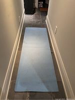 Blue yoga mat laid flat on floor showing length, width, and surface condition