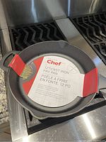 Top view of the 12-inch cast iron skillet with paper label inside, placed on stovetop.