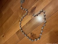 Photo of chunky rhinestone belt laid flat on wooden floor, showing rhinestone links and clasp.