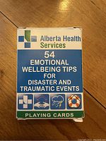 Box for a deck of playing cards titled Alberta Health Services 54 Emotional Wellbeing Tips for Disaster and Traumatic Events.