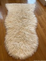 Top side of the cream colored faux sheep skin rug showing long soft synthetic fibers and irregular organic shape.