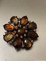 Close-up of Joan Rivers flower brooch with faceted teardrop and oval earth-tone rhinestones and smaller amber rhinestones.