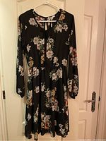 Full front photo showing navy blue dress with floral print, long sleeves, gathered waist and knee-length skirt.