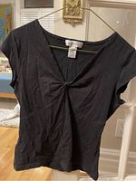 Front view of black short sleeve crop top by Nine West showing twisted detail at chest