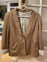 Photo of Philosophy brand coffee-colored women's blazer hanging on hanger, showing front and cuffs with inner lining.