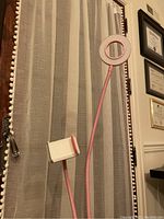 Full view of the pink adjustable ring light and flexible phone holder mounted on a large pink desk clip, seen against a window with blinds and certificates on the wall.