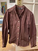Front view of the brown spring/fall coat showing button front closure, patch pockets, and fabric texture