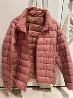 Front open view of salmon colored Uniqlo ultralight down jacket showing quilting and zipper interior.