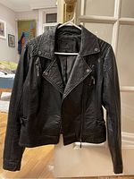 Front view of the black vegan leather jacket showing zipper details and collar.