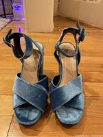 Front view of sky blue crushed velvet high heel pumps showing crossover straps and open toe design.