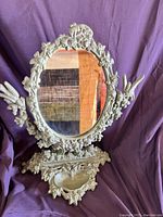 Front view of the vintage wrought iron vanity mirror showcasing floral ornate frame and oval adjustable mirror.