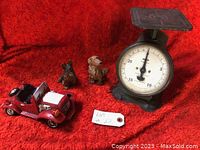 Photo showing the CLIMAX family scale with two dog figurines and small red car on red background