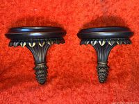 Pair of brown and gold embossed decorative wall sconces shown on a red carpet background.