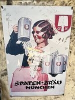 Photo of vintage metal advertising sign for Spaten beer showing a woman holding beer steins and Spaten Bräu München text