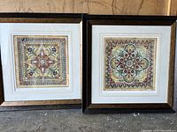 Two framed mandala art prints shown side by side, displaying their colorful geometric and floral designs within white matting and dark brown shadow box frames.