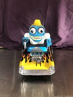 Front-facing view of the battery operated toy car with character driver, showing flame decals and chrome engine detail.