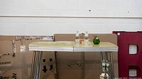 Yellow retro table with assorted glassware, figurine, and lamps displayed on top.