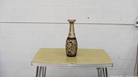 Decorative bottle centered on a yellow textured surface against a white wall background.
