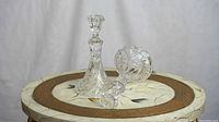 Two clear crystal candle holders with pinwheel pattern design placed on a round table, one holder upright and the other laying on its side.