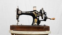 Front-side view of GER sewing machine on wooden base showing decals and medallion