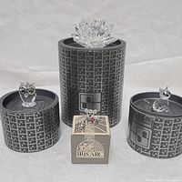 Front view showing four Swarovski crystal figurines: owl on left, cat on right, dog on front center on original box, and crystal flower on larger display cylinder.