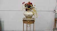 Front view of vase with floral arrangement placed on metal stand, showing details and colors.