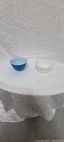 Blue and white vintage Pyrex bowls on a white cloth background side by side.