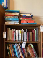 Books on shelves and top of furniture, showing a variety of titles including travel, mindfulness, fiction, English grammar and drawing.