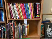 Wide view of two bookshelves containing cookbooks, reference books, and Canadian-themed books, showing titles and various authors.