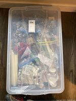 Sealed plastic bin containing various candles and bags of beads