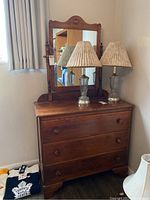 Full view of wooden dresser with attached mirror and two glass lamps on top
