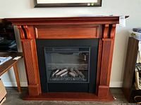 Front view of electric fireplace with wood mantel showing decorative fluted columns and top ledge.