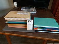 Stack of various journals and notebooks on wooden table with price tag