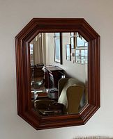 Full view of wooden framed octagonal mirror hanging on a wall showing the depth and finish of the frame.