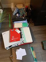 Photo of assorted office supplies including notebooks, papers, hole punch, and index cards