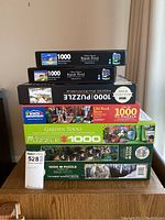 Photo of stacked puzzle boxes showing variety of puzzles included in lot